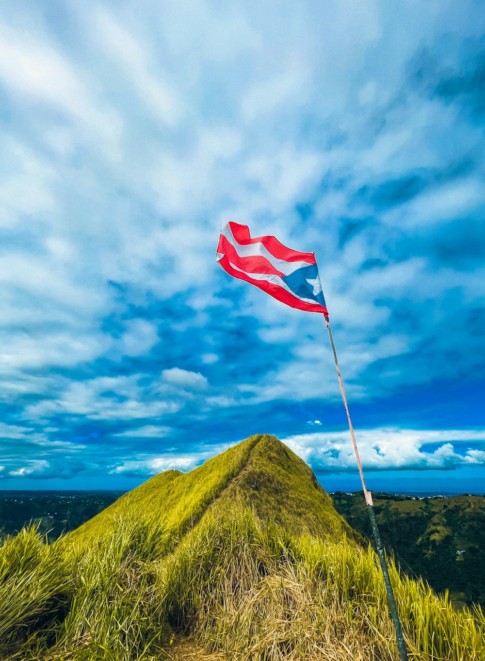 a red and white flag flying on a grassy hill