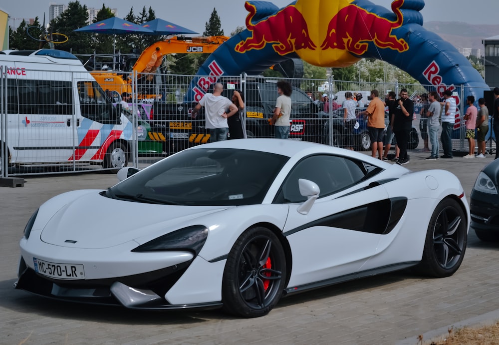 a white sports car parked in front of a crowd of people