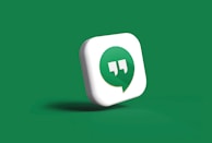 A 3D icon featuring a green speech bubble with white quotation marks inside is set against a solid green background. The speech bubble is slightly tilted and appears to be casting a subtle shadow.