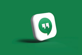 A 3D icon featuring a green speech bubble with white quotation marks inside is set against a solid green background. The speech bubble is slightly tilted and appears to be casting a subtle shadow.