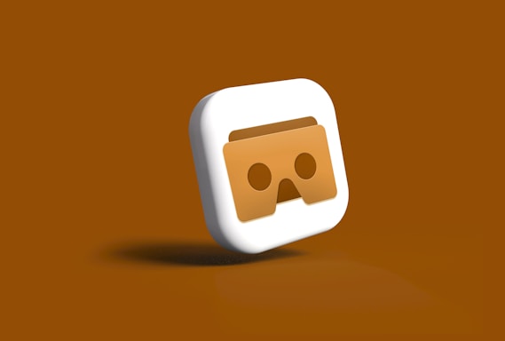 A three-dimensional icon featuring a stylized pair of VR goggles in the center. The goggles appear in a brownish shade on a square-shaped background with smooth, rounded edges. The icon is set against a monochromatic brown backdrop, enhancing the visual focus on the goggles.