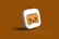 A three-dimensional icon featuring a stylized pair of VR goggles in the center. The goggles appear in a brownish shade on a square-shaped background with smooth, rounded edges. The icon is set against a monochromatic brown backdrop, enhancing the visual focus on the goggles.