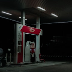 A close-up photo of a red fuel pump nozzle dispensing Pertamax fuel.