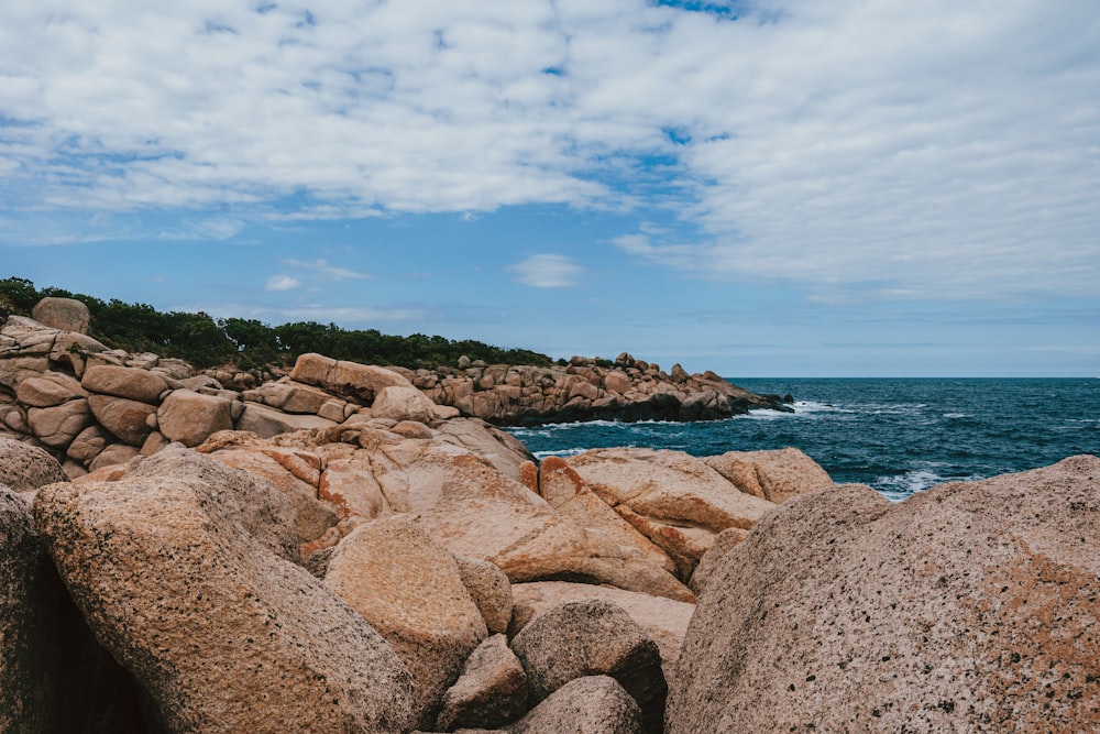 a rocky beach with a body of water in the background