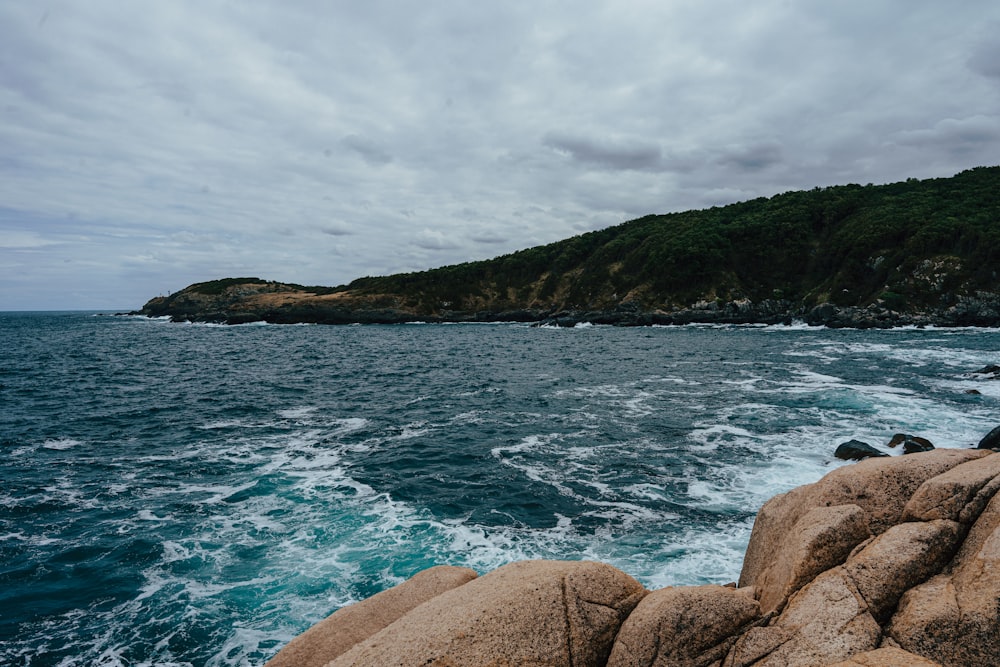 a rocky beach with a hill in the background