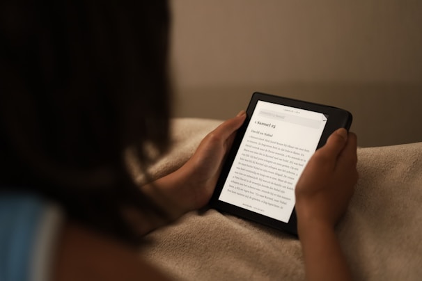A close-up of a person reading a digital booklet on a tablet in a cozy home setting