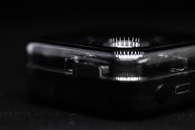 A close-up view reveals part of a clear, plastic-cased electronic device with a circular array of white LED lights. The focus is on the device's corner, highlighting intricate details such as small connectors and buttons.