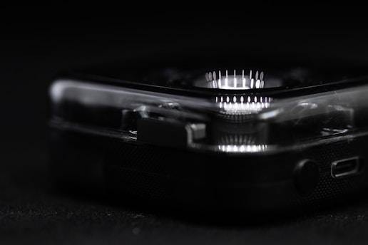 A close-up view reveals part of a clear, plastic-cased electronic device with a circular array of white LED lights. The focus is on the device's corner, highlighting intricate details such as small connectors and buttons.