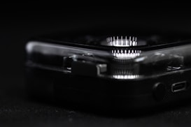 A close-up view reveals part of a clear, plastic-cased electronic device with a circular array of white LED lights. The focus is on the device's corner, highlighting intricate details such as small connectors and buttons.