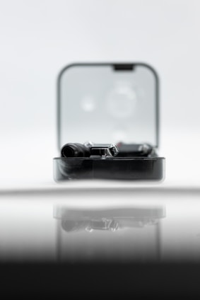 A sleek black leather mate kit with shiny silver details and an elegant futuristic black case on a wooden table.