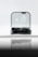 A sleek black gadget is partially enclosed in a clear rectangular case, reflecting on a glossy surface. The backdrop is soft and out-of-focus, creating a minimalist and modern aesthetic.