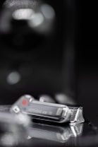 A close-up of a digital device with the word 'Nothing' inscribed on it, featuring a metallic and sleek design with a reflective surface. There are soft blurred lights in the background, adding a hint of mystery.