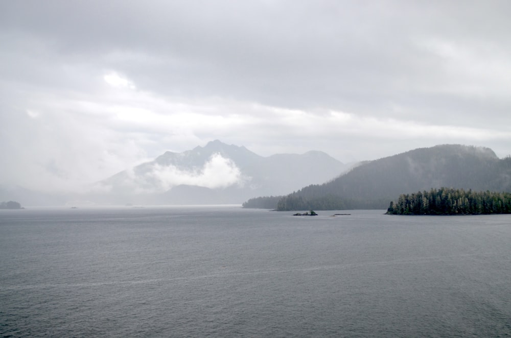 a body of water with boats in it and mountains in the back