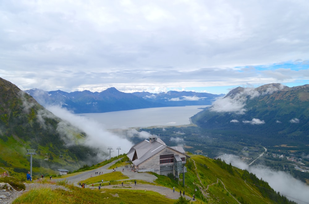 a house on a hill by a lake and mountains