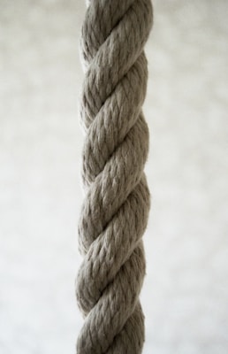 A thick, twisted rope made from natural fibers in a close-up view, highlighting its texture and braided structure against a soft blurred background.