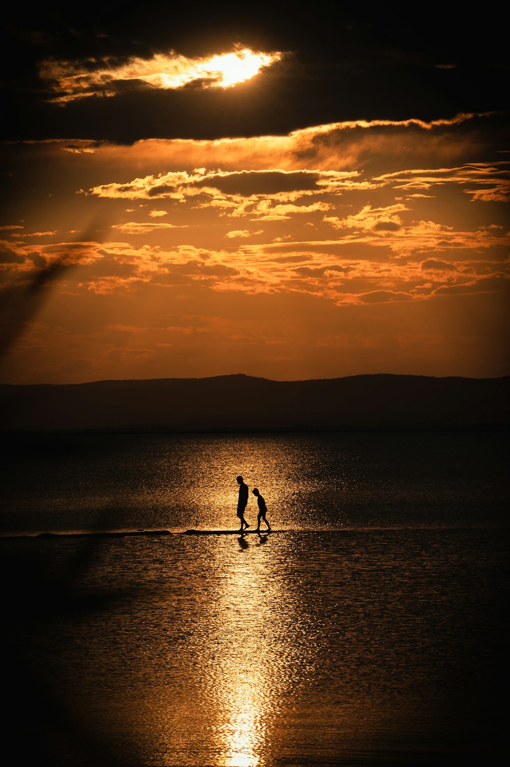 a couple of people standing on a beach under a cloudy sky