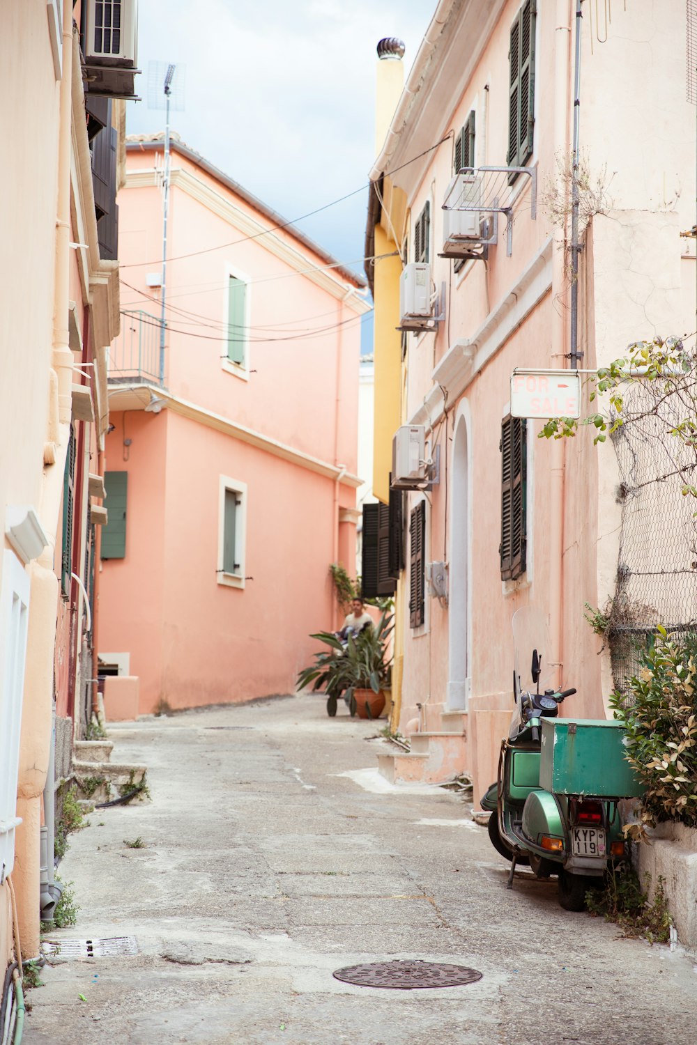 a green tractor parked in a narrow alley between buildings