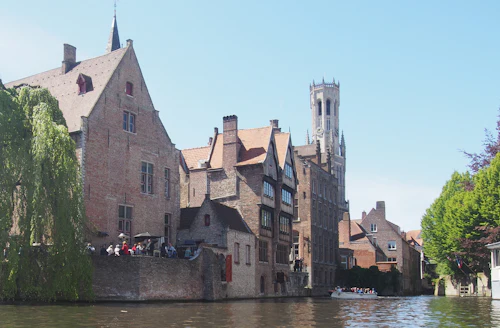 Le beffroi de Bruges au-dessus des maisons, depuis le canal