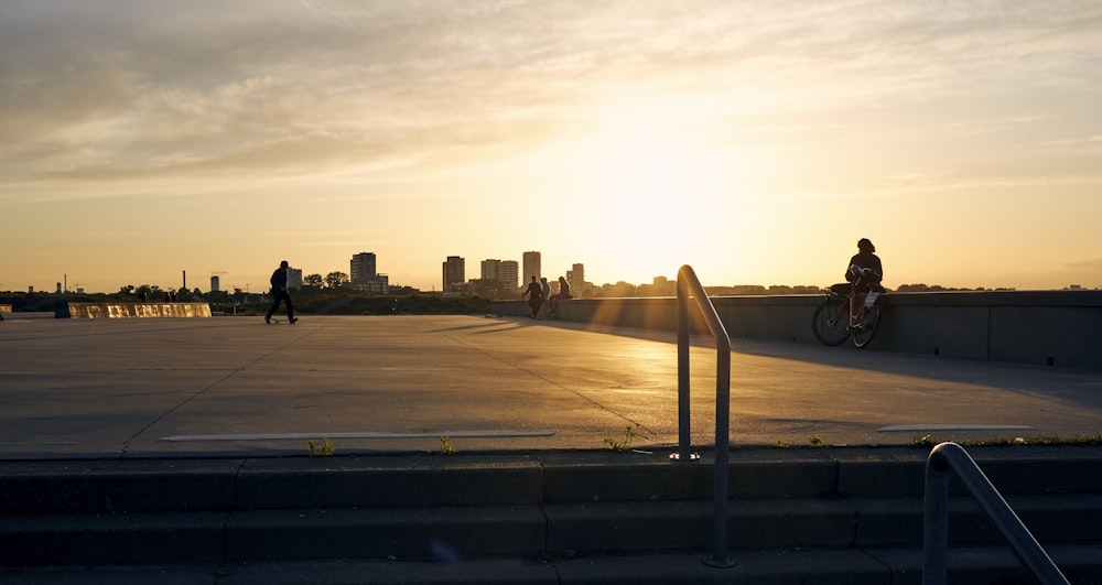 a group of people riding bikes on a concrete area with a city in the background