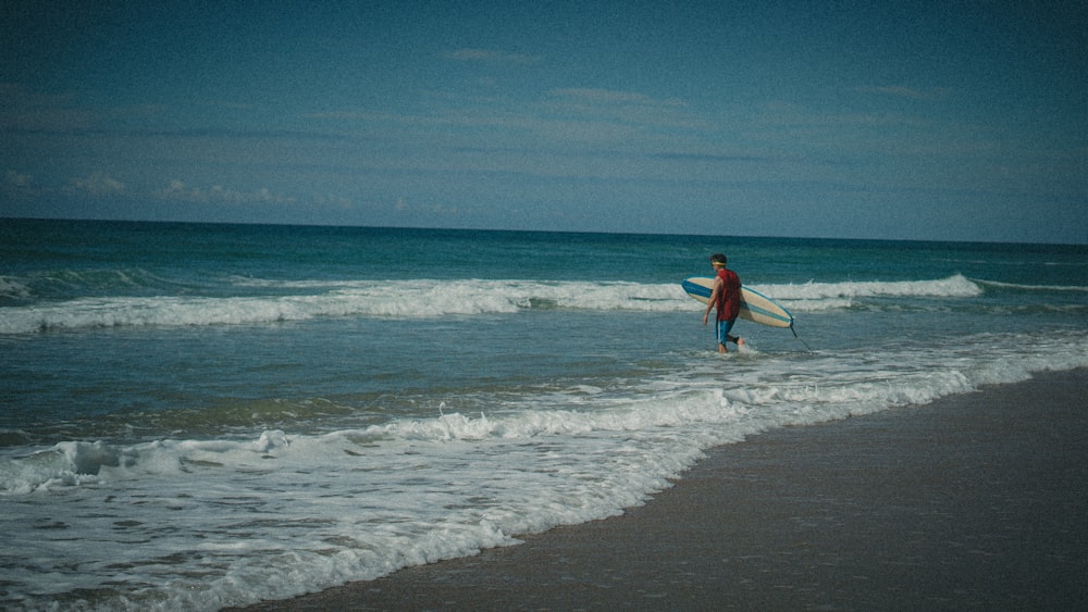 um homem carregando uma prancha de surf em uma praia