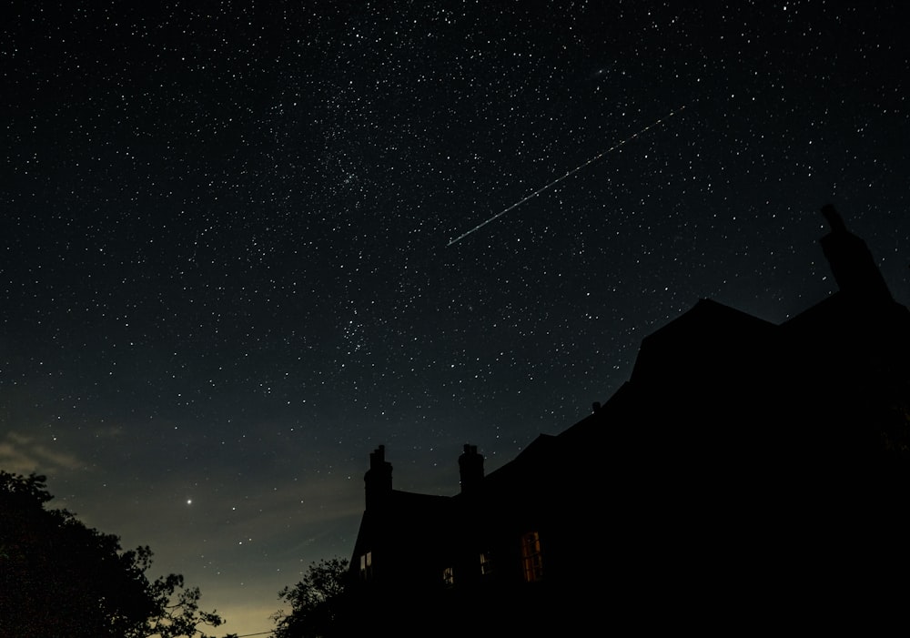 a silhouette of a house and stars in the sky