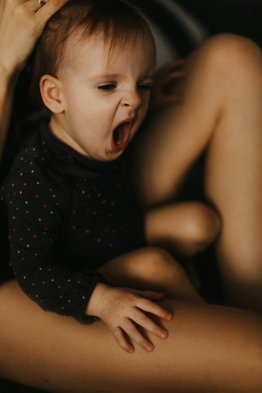 a baby crying on a person's lap