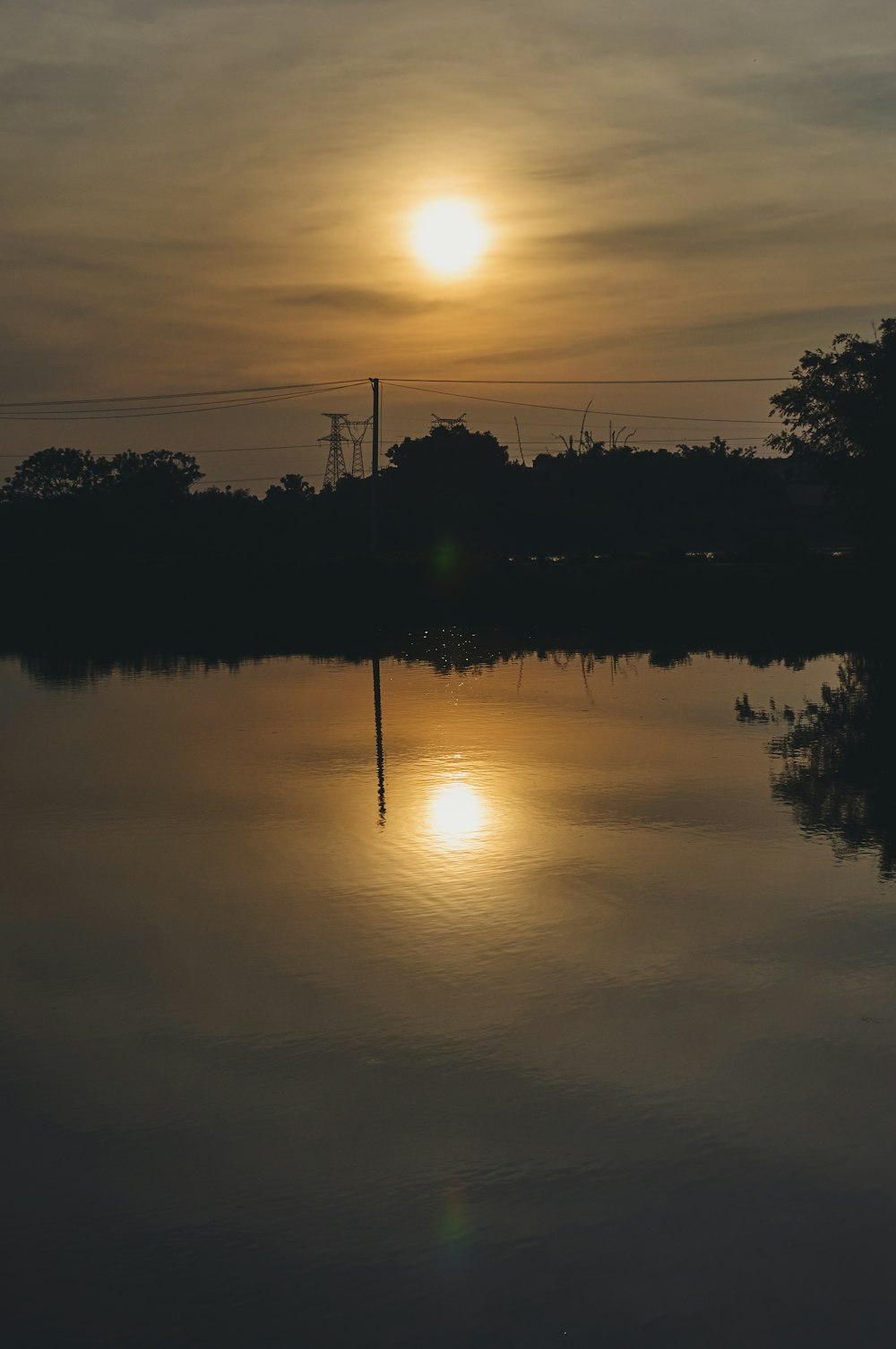 a body of water with trees and a sunset in the background