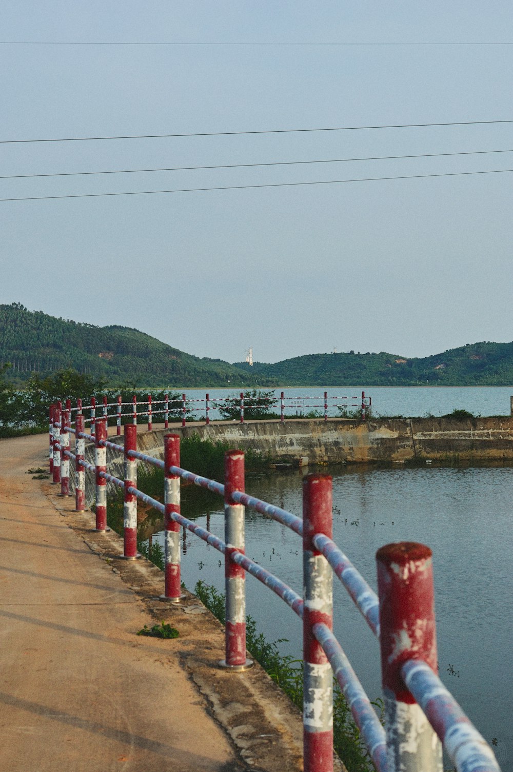 a red fence with white poles and a body of water in the background