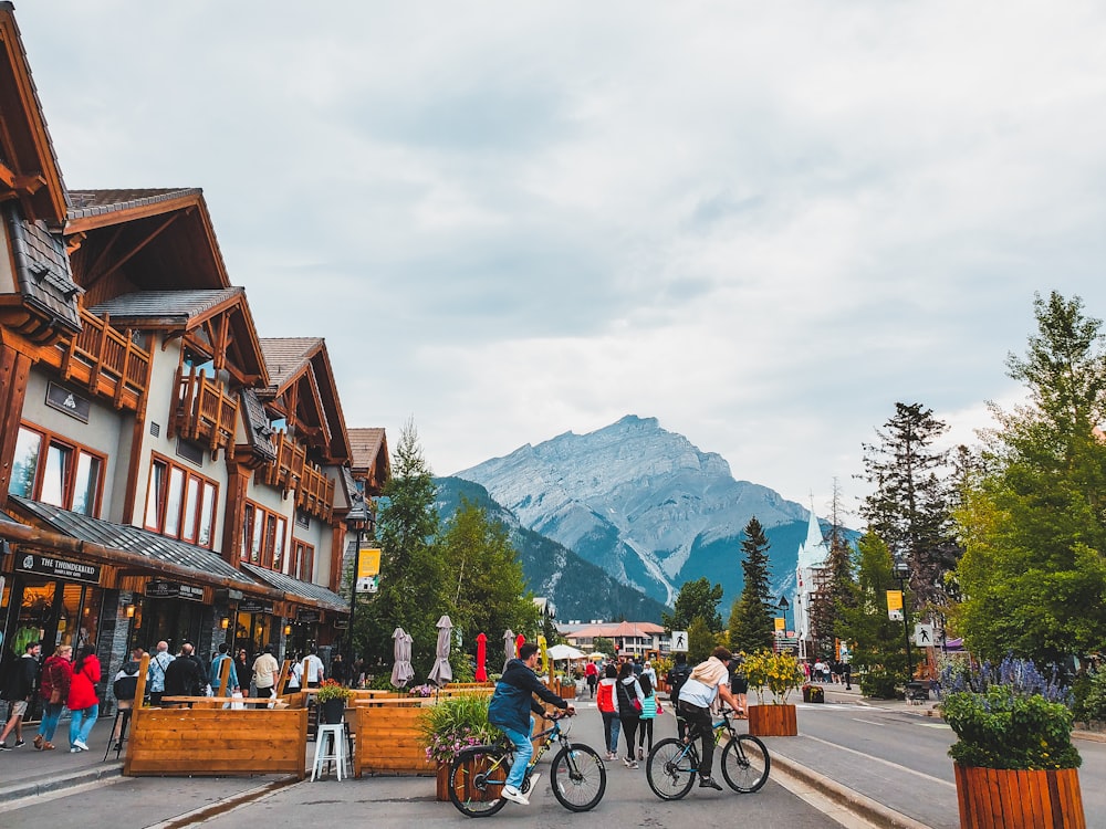 a group of people riding bikes on a street with a mountain in the background