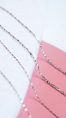 Delicate stainless steel chains arranged artistically on a soft fabric.