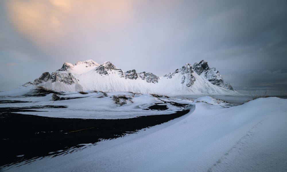 a snowy landscape with a body of water and mountains in the background