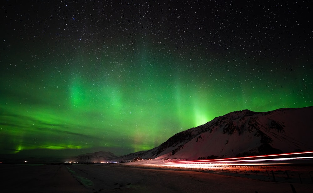 a road with a mountain and a green sky in the background