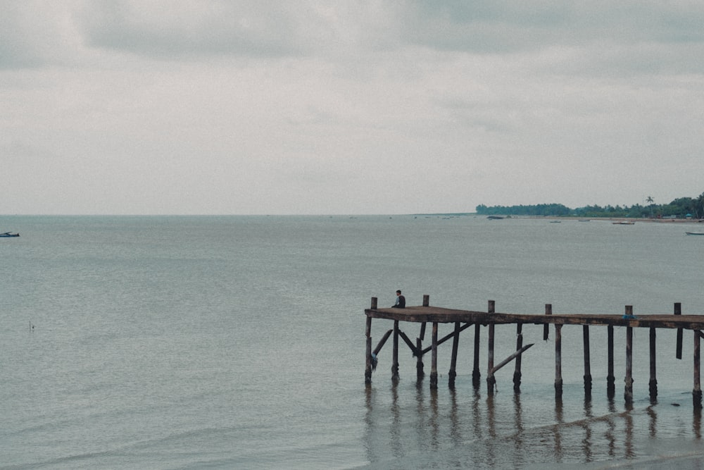 a person sitting on a dock in the water