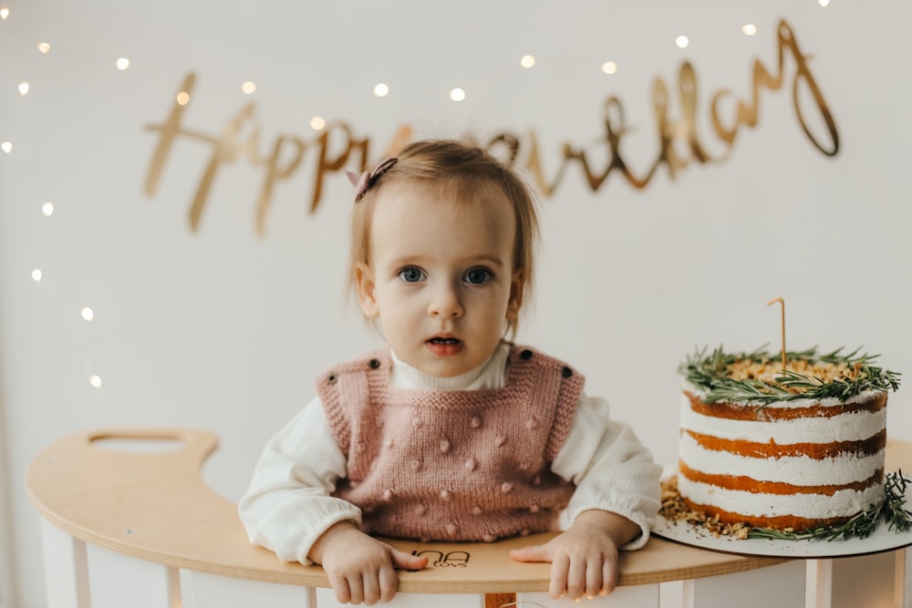 a baby sitting at a table with a cake