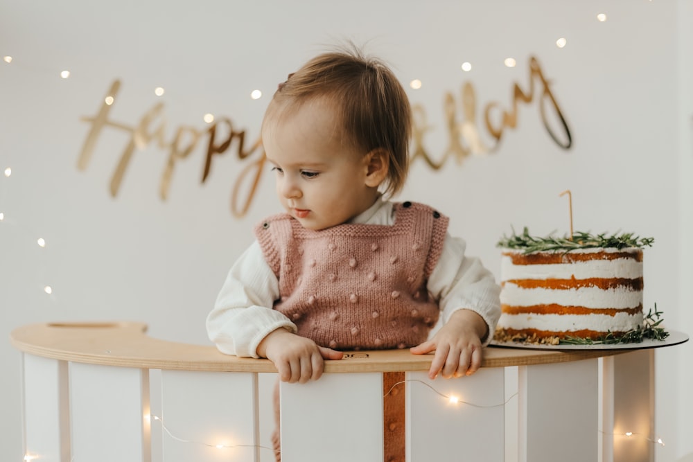 a baby sitting at a table with a cake