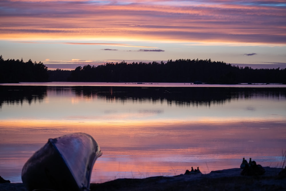 a body of water with trees and a sunset in the background