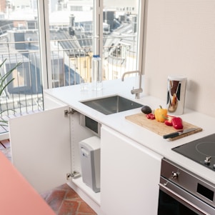 A modern kitchen workspace with eco-friendly utensils and fresh vegetables on a wooden cutting board.