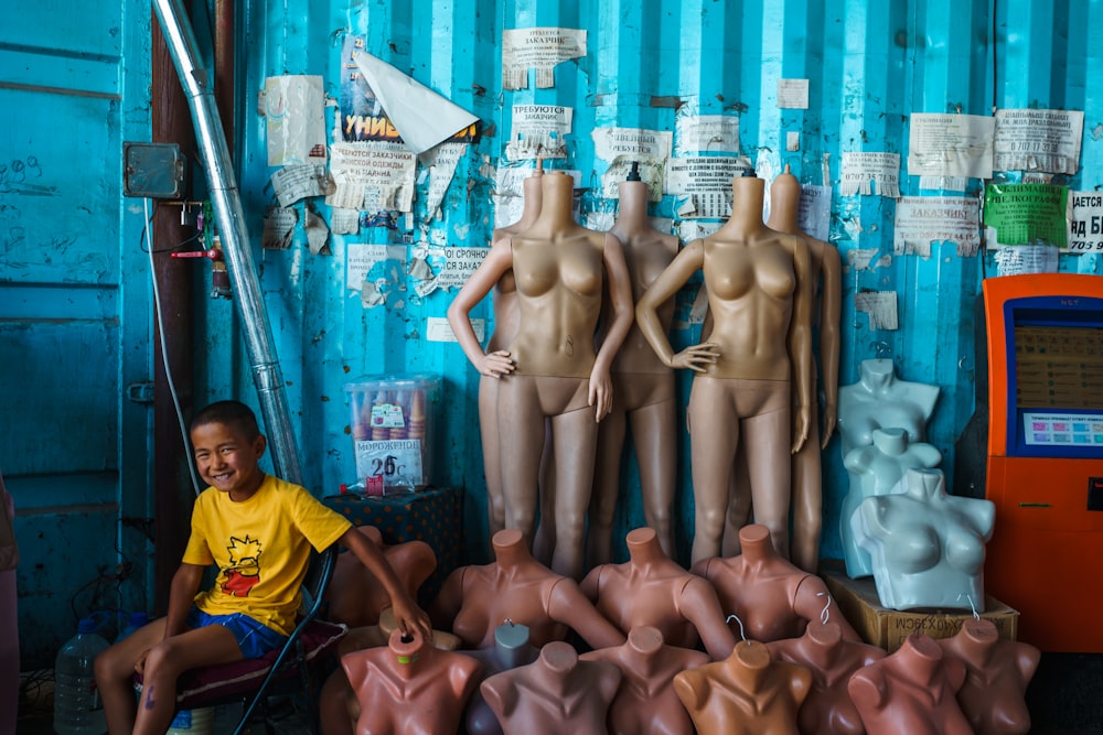a boy sitting in a chair next to a group of clay statues