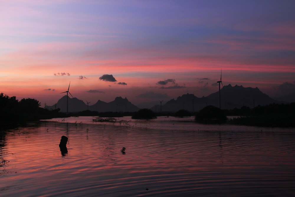 a body of water with trees and mountains in the background