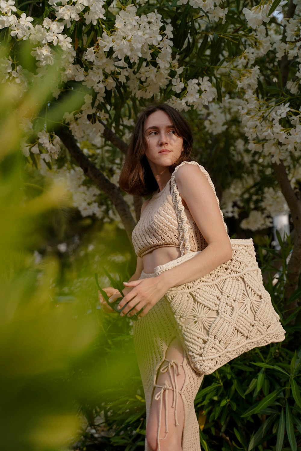 a woman standing in front of a tree with white flowers