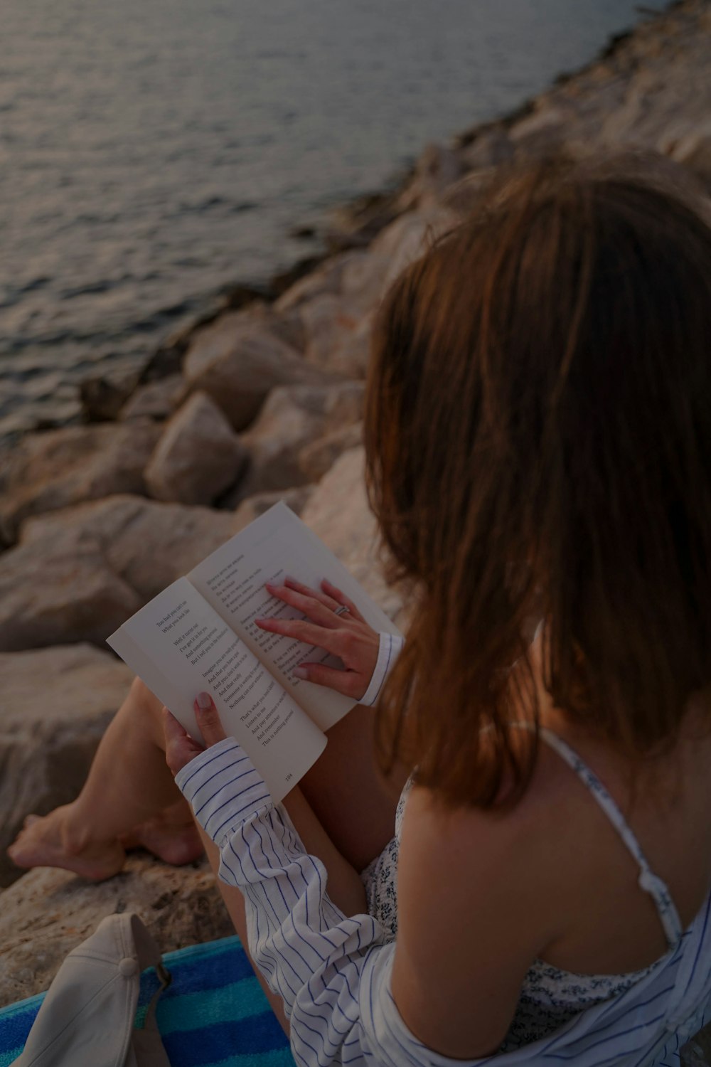 a woman reading a book on a beach