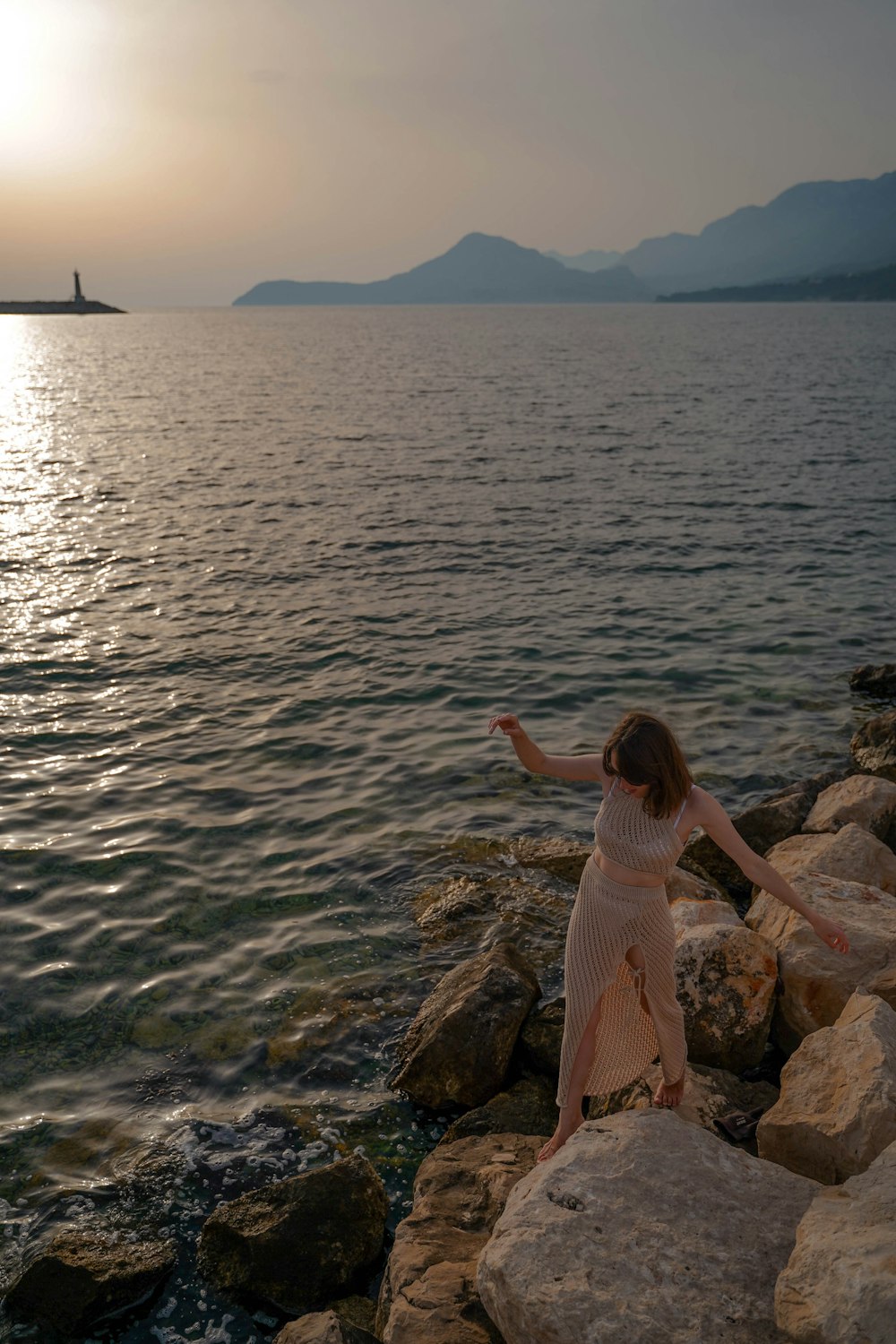 a person standing on rocks by the water with a boat in the background