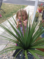 Child playing in a sun-dappled garden with terracotta pots around.