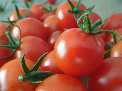 Close-up of ripe crimson tomatoes and fresh produce from a local market, evoking freshness and authenticity.