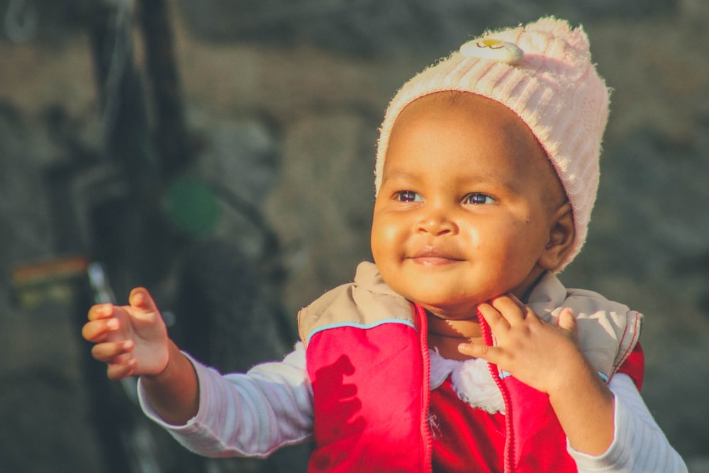 a baby wearing a pink and white outfit and holding a small object