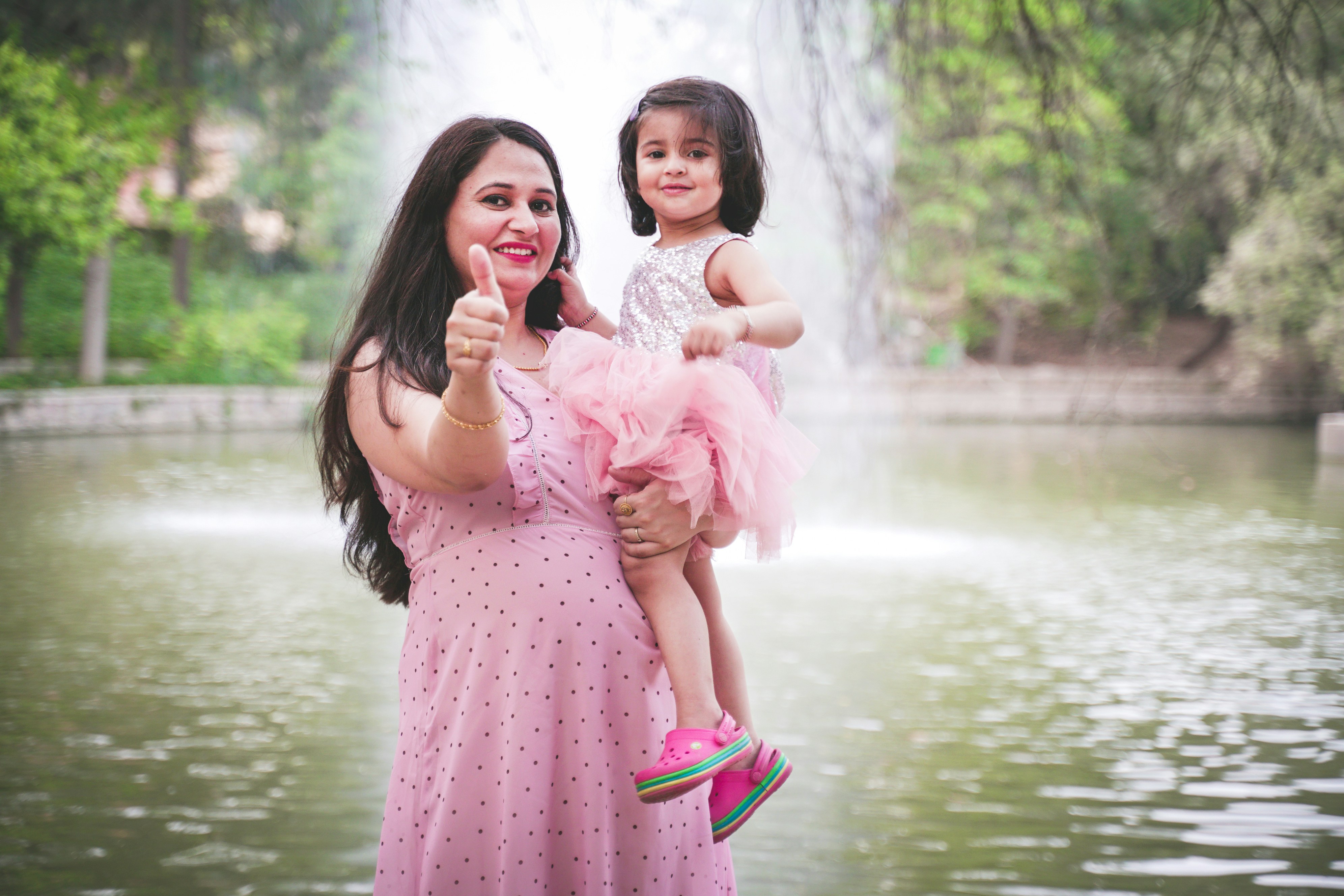 seseorang menggendong seorang gadis dengan gaun merah muda di depan air terjun