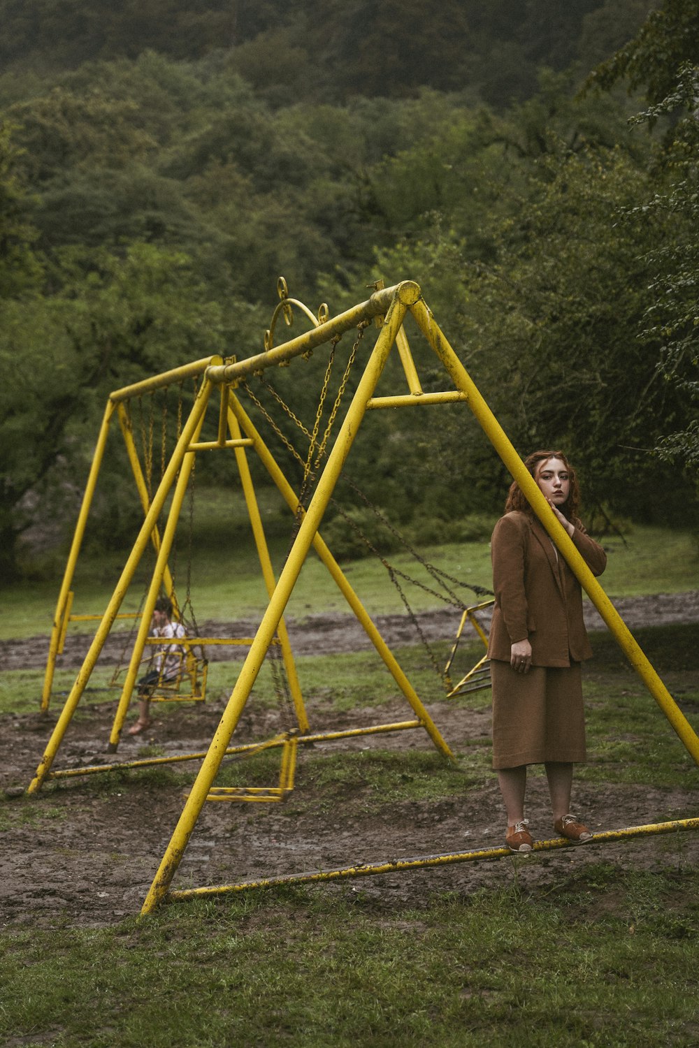 a person standing next to a yellow swing