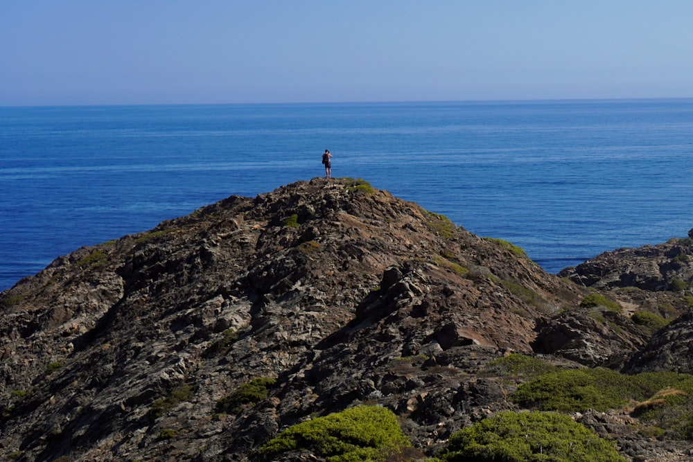 una persona in piedi su una scogliera rocciosa