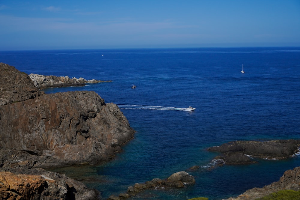 a rocky beach with a sailboat