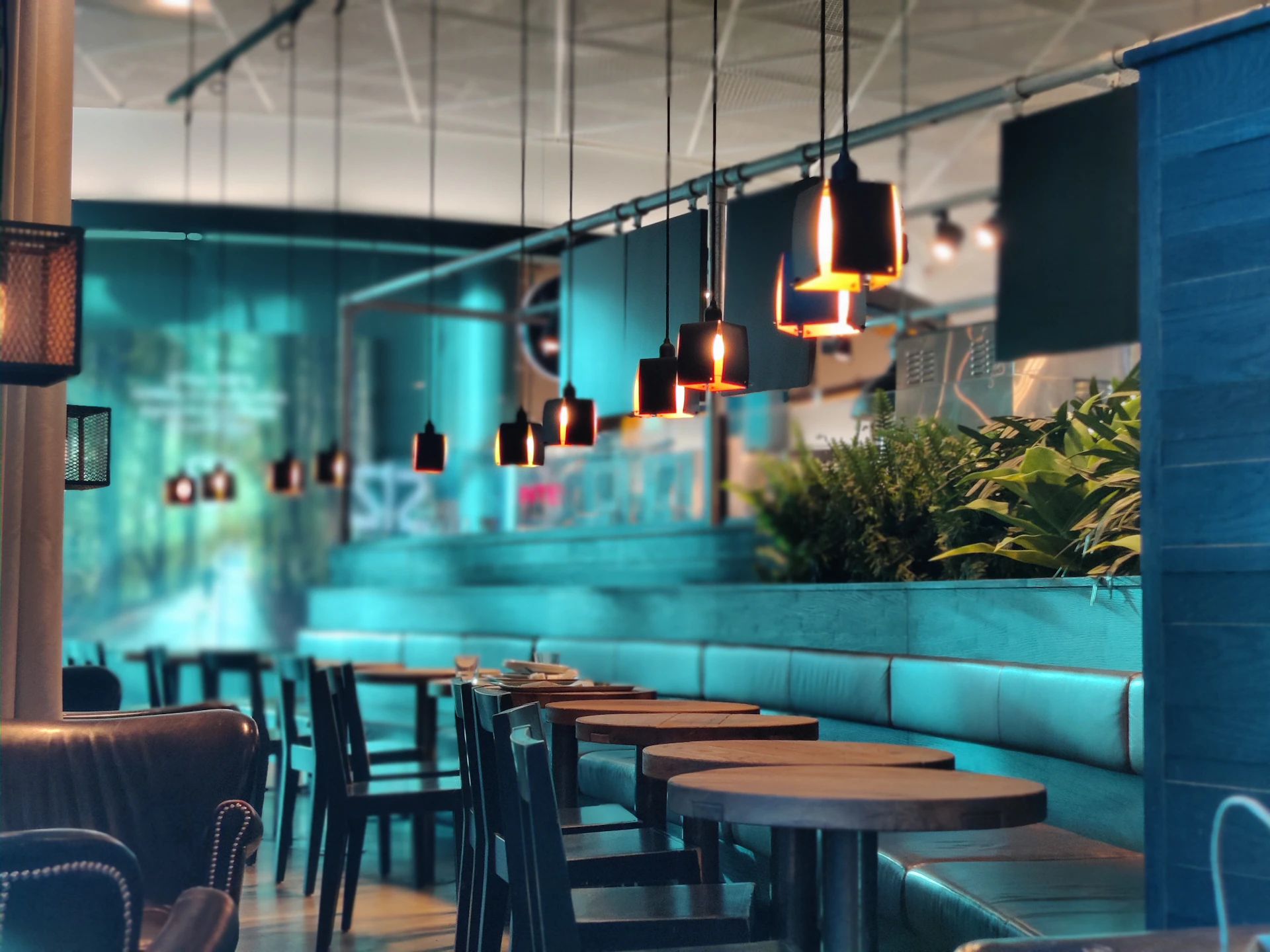 An elegant restaurant interior featuring warm pendant lights and subtle purple and teal accents.